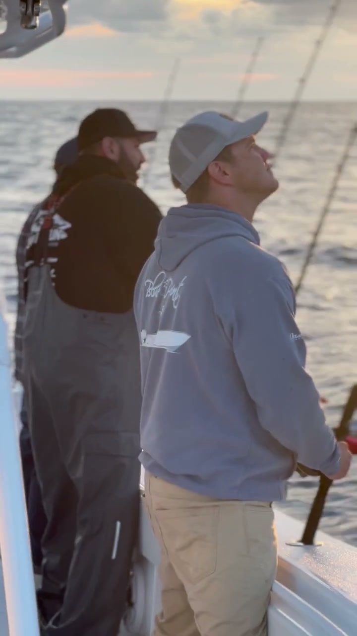 Crew wearing printed hoodies aboard at sunset